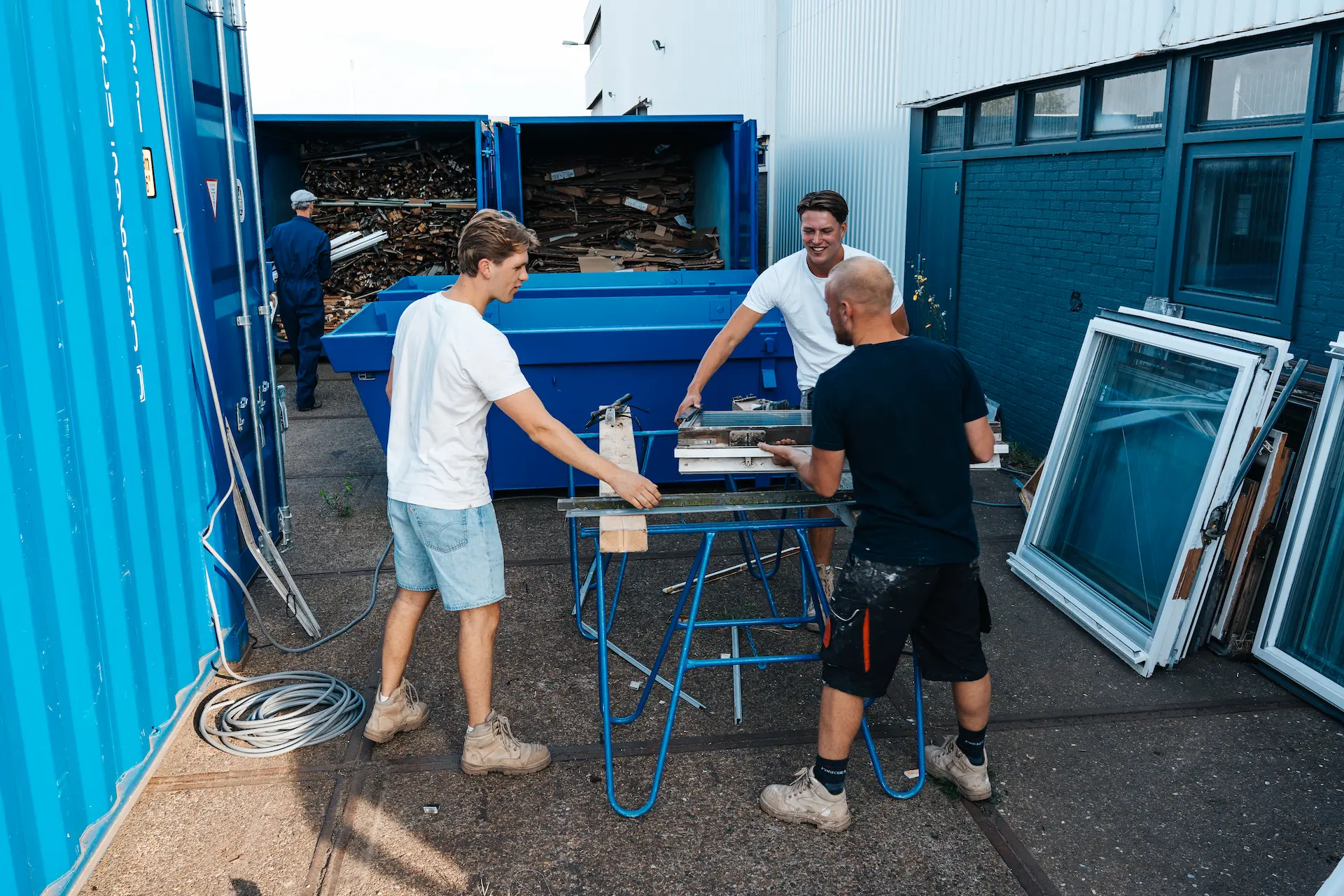 Een oud dakraam wordt naar de recyclingcontainer gedragen